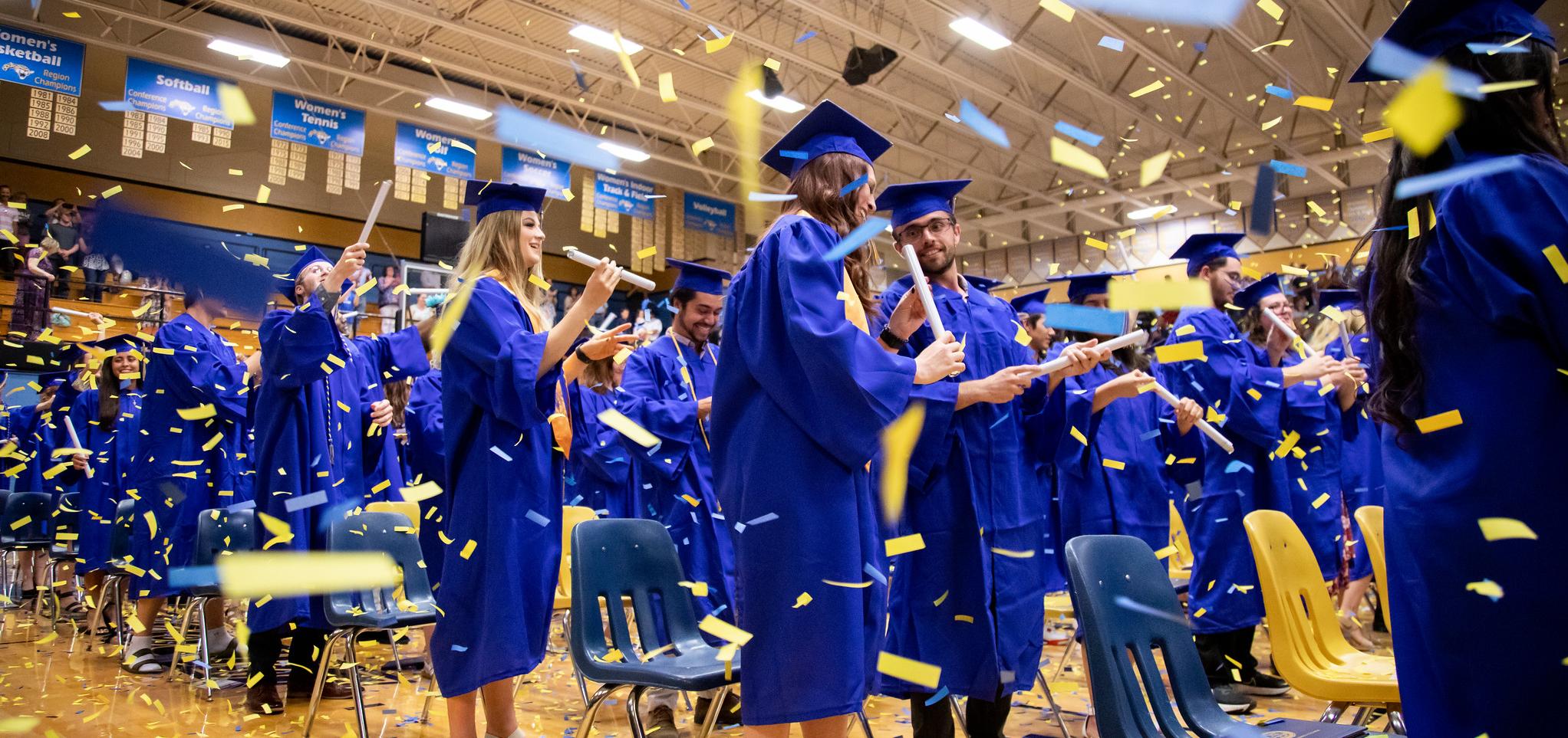 Graduates throw confetti at the conclusion of commencement 